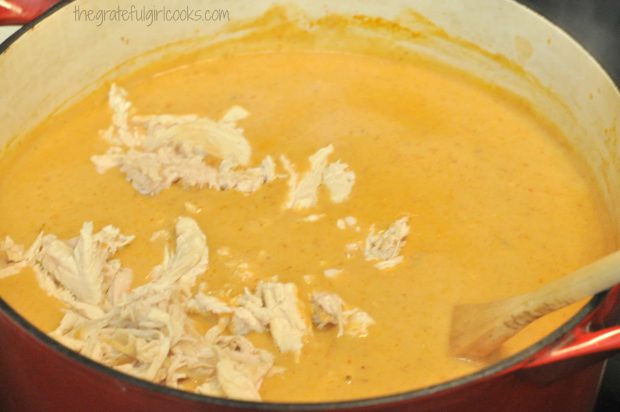 Adding shredded chicken to Chili's chicken enchilada soup in large saucepan.
