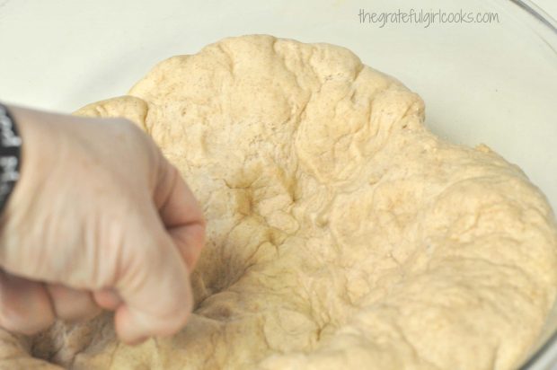Risen dough is punched down to deflate, before forming cinnamon crunch bagels.