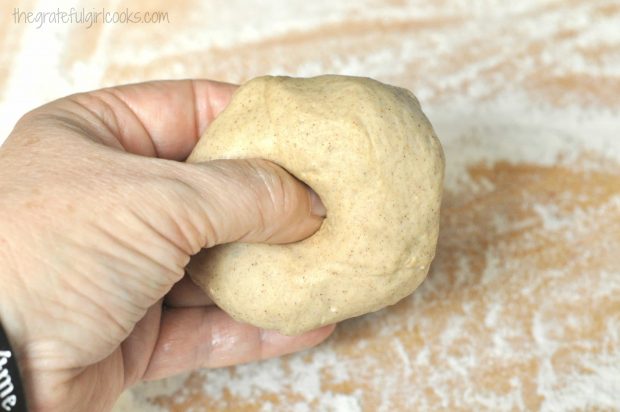 A hole is punched into the bagel dough ball, using a thumb.