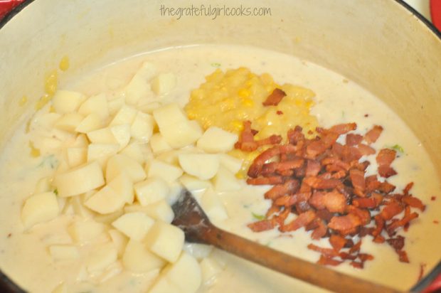 Corn, bacon and potatoes are added to chowder in soup pot.