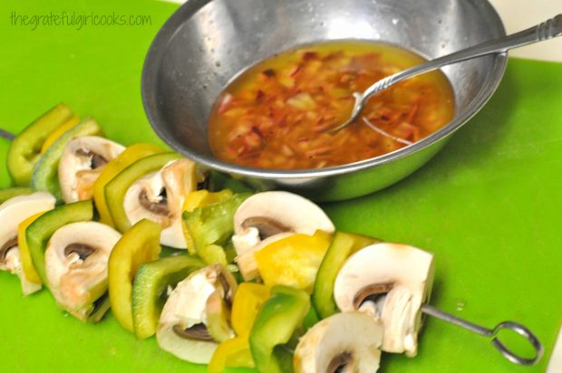 Mushroom and pepper kabobs on skewers, with marinade in bowl