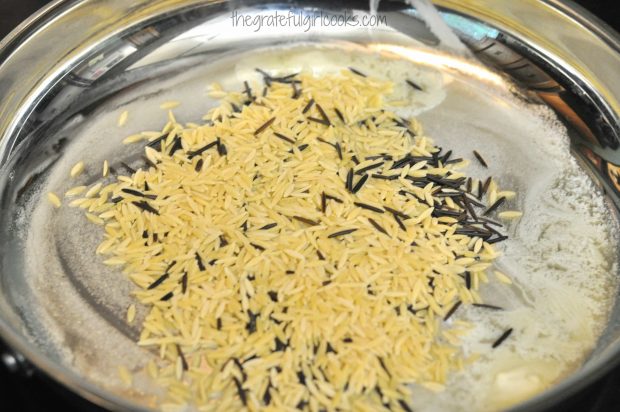 Orzo and wild rice cook in butter in skillet