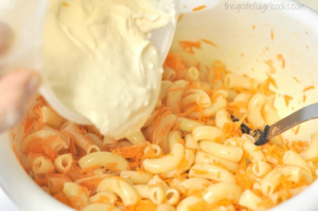 Mayonnaise mixture added to Hawaiian macaroni salad in bowl.