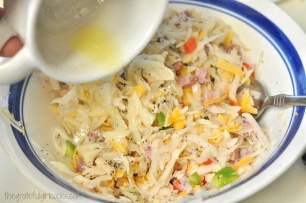 Melted butter is added to the uncooked hash brown mixture and stirred in.