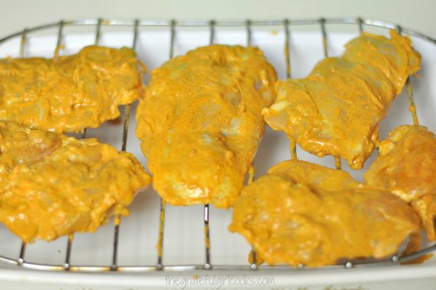 Tandoori chicken pieces are placed on a wire rack, and is ready for the oven.