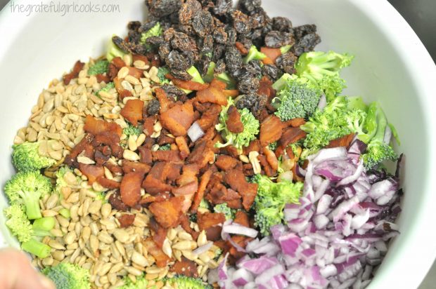 Ingredients for broccoli salad in large white mixing bowl.