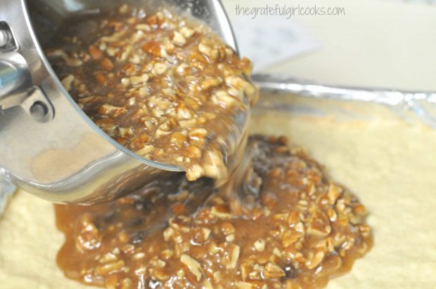 The filling for chocolate pecan pie bars is poured onto crust in pan.