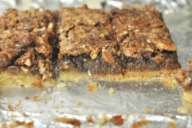 Close up photo of a few Chocolate Pecan Pie Bars on aluminum foil.