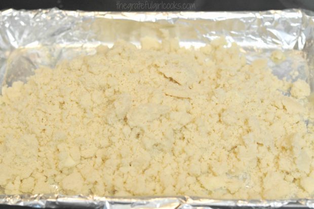 The shortbread crust crumbles are placed in foil lined baking sheet.