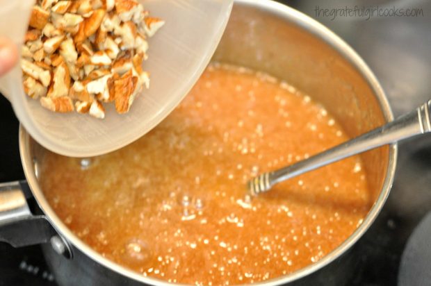 Chopped pecans are added to chocolate pecan pie bars filling in pan.