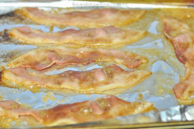 The bacon strips are turned halfway through baking time.