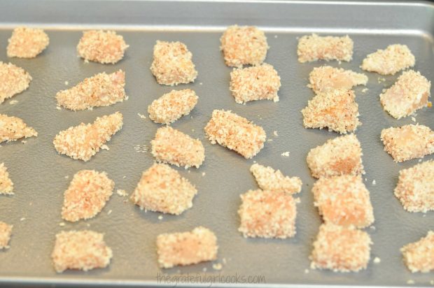 Panko-coated chicken pieces are placed on a greased baking sheet for baking.