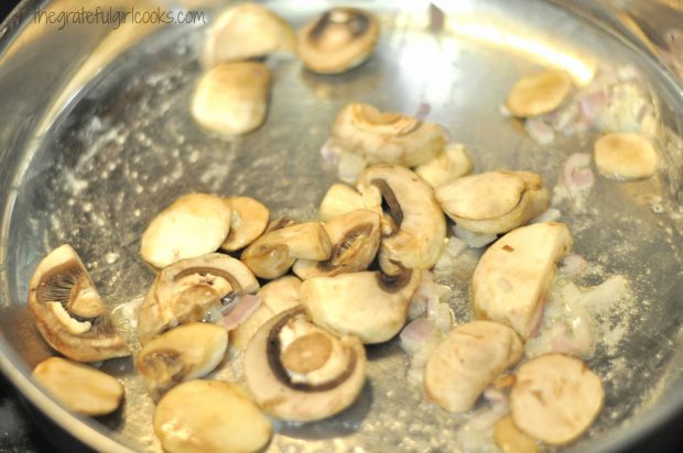 Mushrooms and red onions cooking in a large skillet.