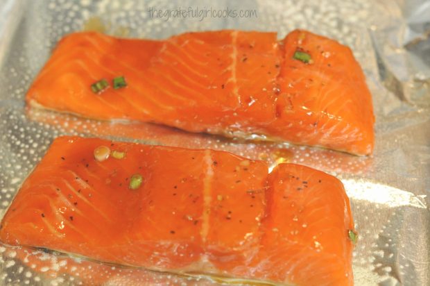 Marinated salmon fillets are placed on pan skin side down for broiling.