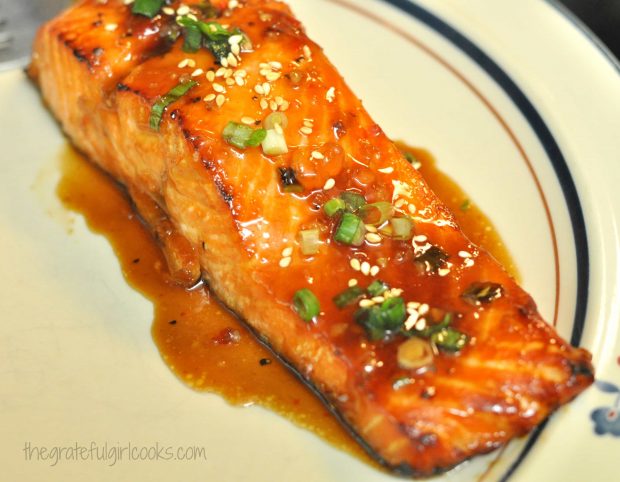 Sweet Chili Glazed Salmon is topped with sesame seeds, green onions & sauce to serve.