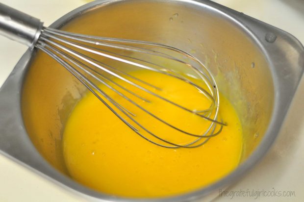 Egg yolks in metal bowl, with whisk