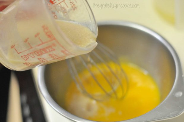 Pouring brown sugar and half and half into egg yolks in bowl