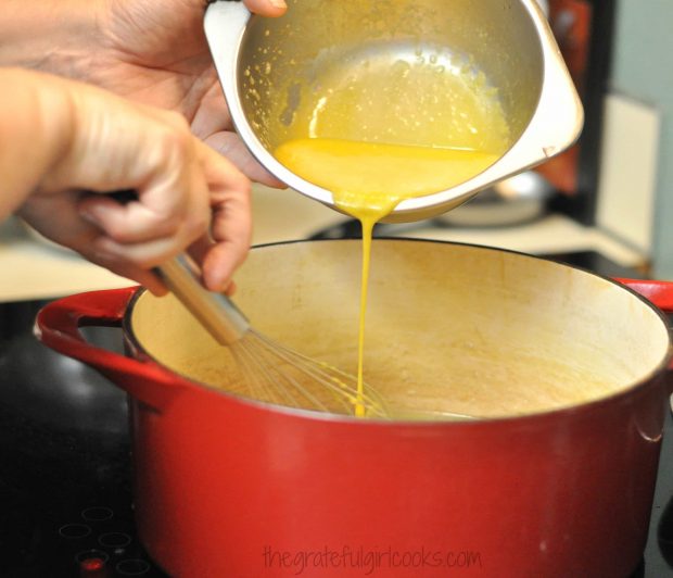 Tempered egg yolks for ice cream poured into red saucepan