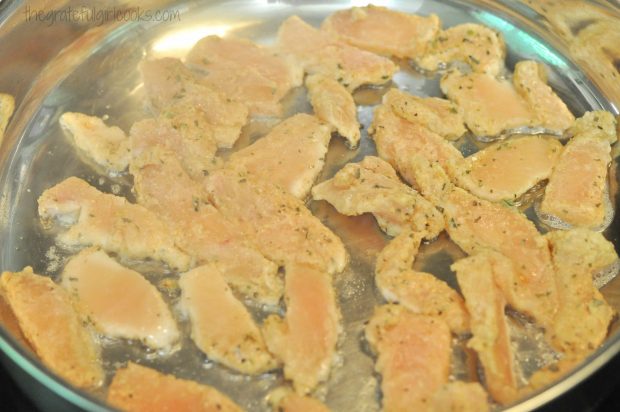 The slices of chicken are pan-seared in coconut oil in large skillet.