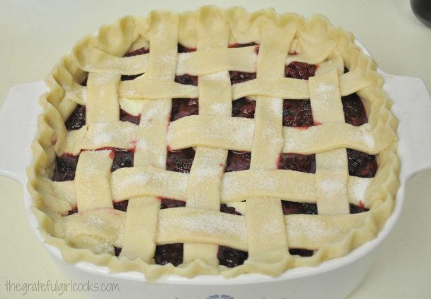 Top lattice crust is arranged on deep dish boysenberry pie.