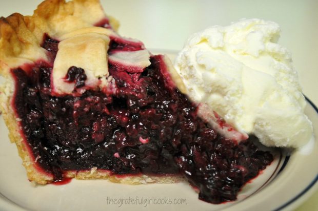 Deep dish boysenberry pie with a scoop of vanilla ice cream