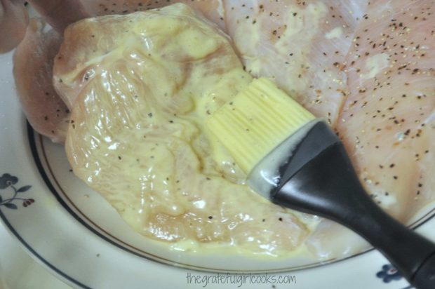 Mayonnaise is brushed onto seasoned chicken breasts, to coat