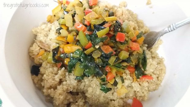 The cooked veggies are added on top of the cooked quinoa in a bowl.