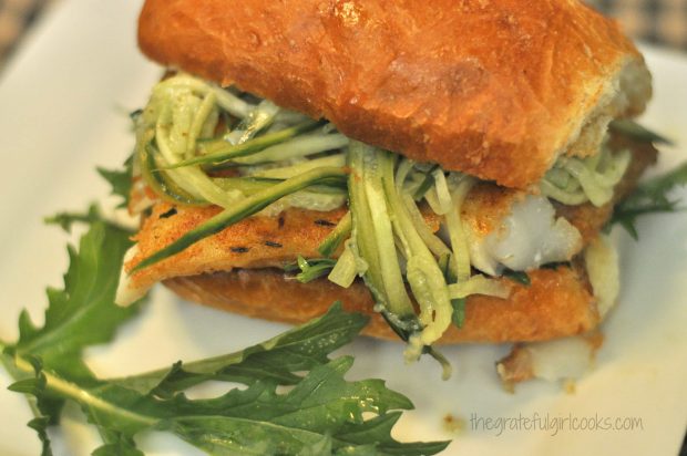 Thinly sliced marinated cucumbers are added to spicy fish sandwich