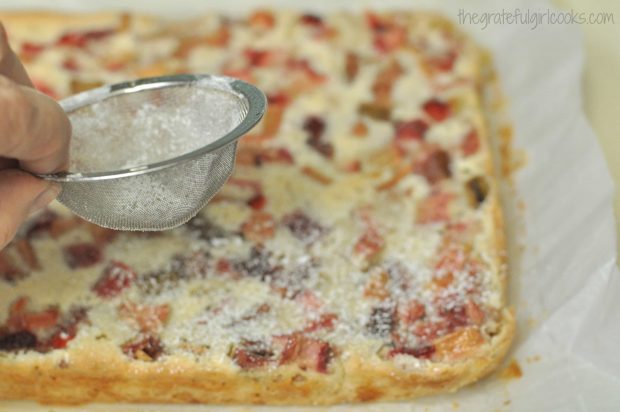 Powdered sugar is sifted over the baked dream bars.