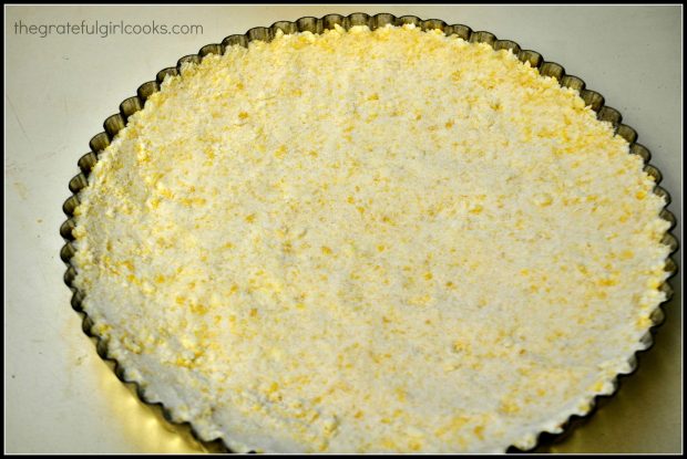 Shortbread crust is packed into a tart pan.