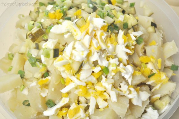 Potatoes, pickles, boiled egg, green onions in bowl for potato salad.