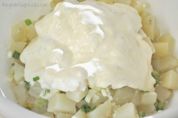 Salad dressing poured over potato salad, then mixed together.