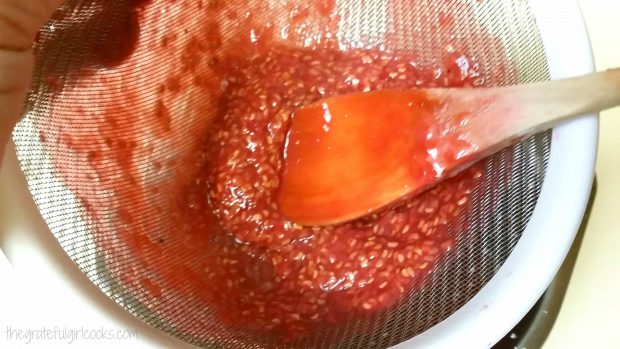 The sauce is forced through a mesh strainer, leaving raspberry seeds behind.