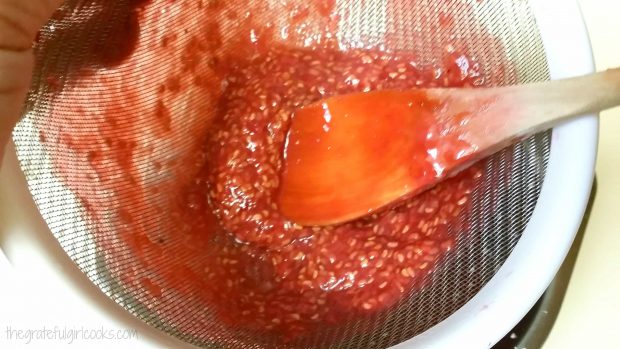 The sauce is forced through a mesh strainer, leaving raspberry seeds behind.