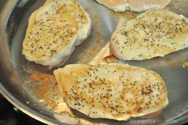 Browned chicken breasts cooking in skillet.