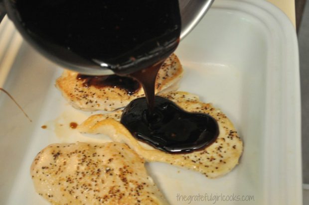Teriyaki sauce poured over cooked chicken breasts in white baking dish