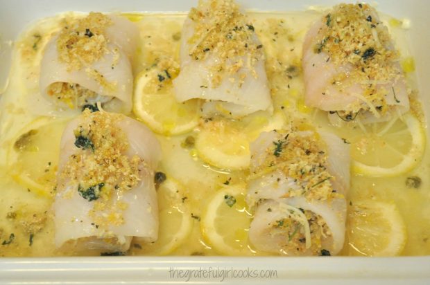 Fish rolled up on top of lemon slices in white baking dish