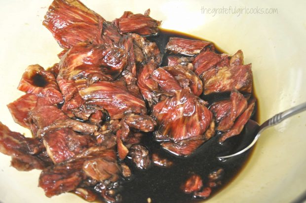 Raw beef strips for beef jerky, marinating in bowl.