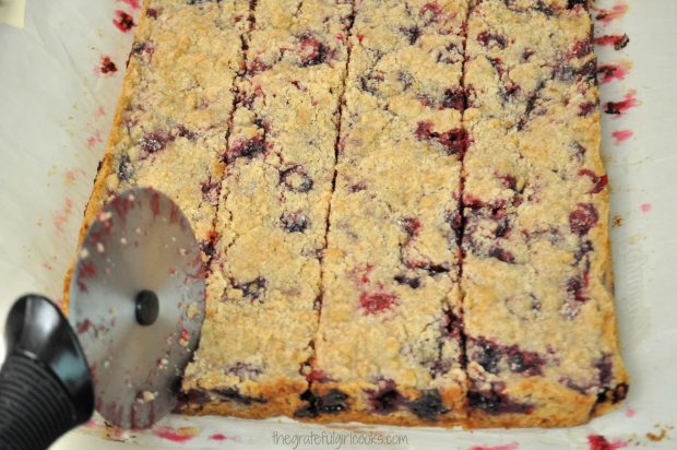 Blackberry bar cookies are cut into squares with pizza cutter