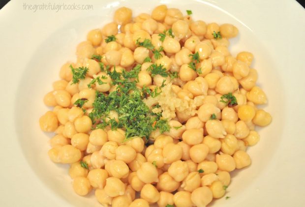 Chickpeas mixed with lemon juice, olive oil and parsley in bowl
