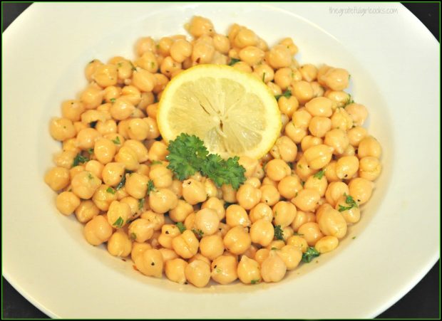 Lemony chickpea salad with parsley and lemon garnish in white bowl