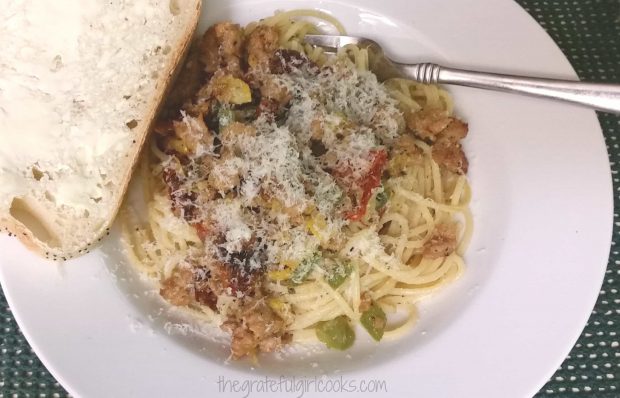 A slice of buttered sourdough bread is served along with the pasta with Italian sausage.