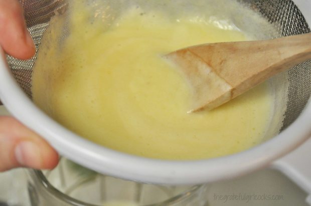 Blended pineapple juice is drained through a sieve to remove pulp.