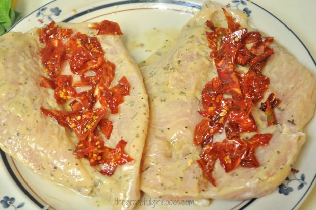 Sun dried tomatoes are placed on one side of the chicken breast.