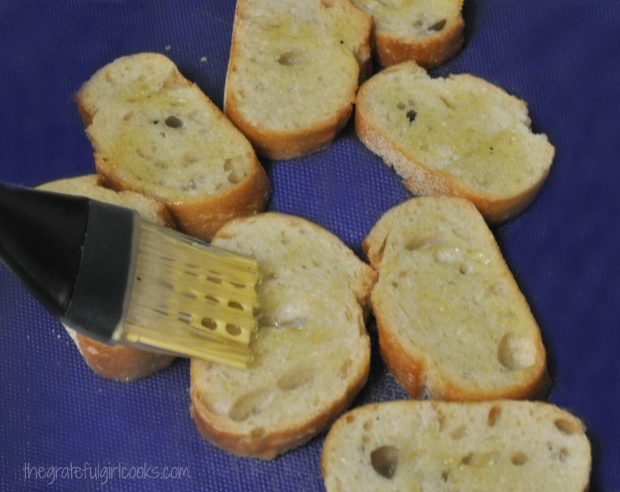 Baguette slices are brushed with olive oil.