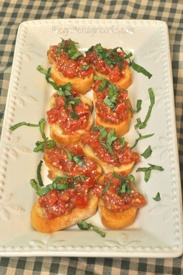 Classic Bruschetta is garnished with thinly sliced basil, then served on a platter.