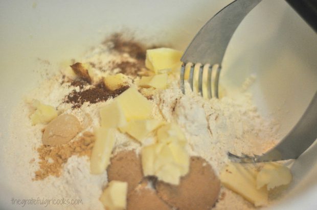 Cold butter is cut into dry ingredients for gingerbread scones, with a pastry cutter.