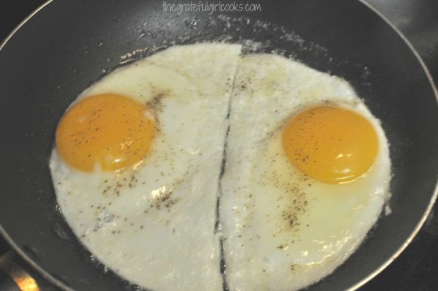 Eggs are fried for bagel breakfast sandwich.