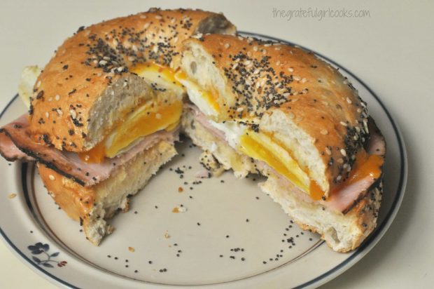 Bagel breakfast sandwich, cut in half, on plate.