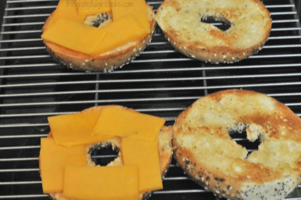 Thin cheese slices are placed on bagel halves.